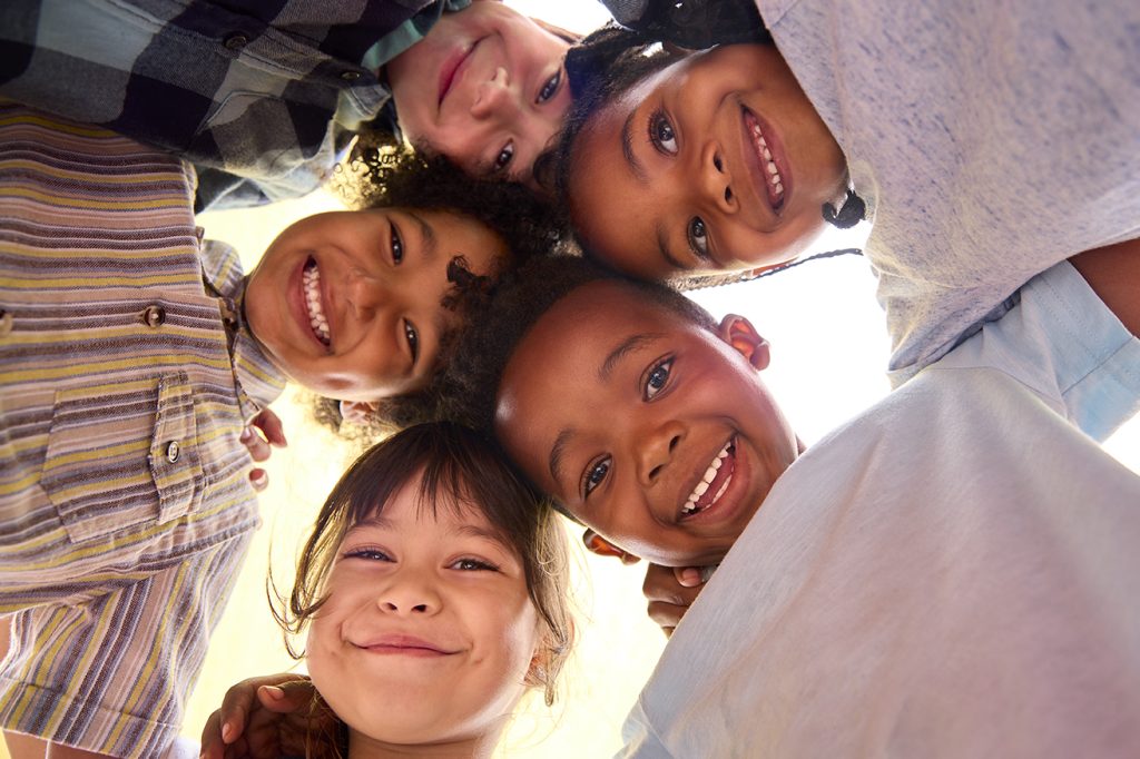 Low Angle Portrait Of Smiling Multi-Cultural Children Looking Do